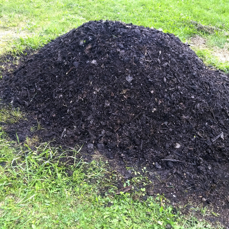 rich black compost pile om yellow green grass